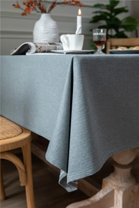 Close-up of light gray herringbone linen-texture tablecloth with soft drape and neat edges