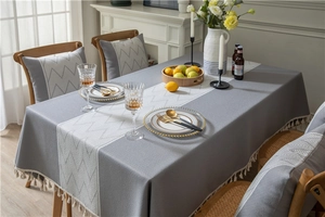 Detail view of jacquard geometric pattern and white fringe tassels on gray tablecloth