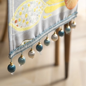 Modern grey polyester table runner with yellow floral patterns and blue ball fringe tassels