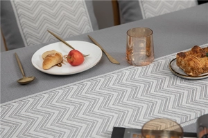 Macro shot of grey wave pattern table runner with textured jacquard fabric and fringe detail