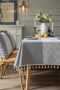 Detail of grey jacquard tablecloth with chevron pattern band and white fringe edges