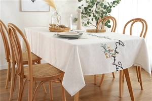 Close-up of embroidered linen tablecloth featuring elegant floral motifs and cursive script