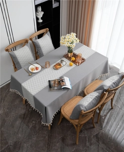 Detailed view of the wavy jacquard texture and white fringe tassels on the grey tablecloth