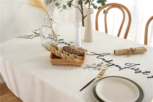 Close-up of rustic beige tablecloth featuring floral embroidery and artistic lettering