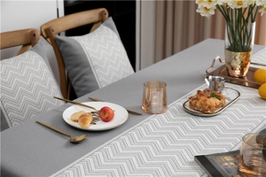 Detail showing jacquard herringbone pattern and wave tassel on a grey fabric tablecloth