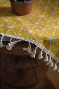 Detail of yellow geometric pattern curtain with fringe tassel edge on a wooden stool