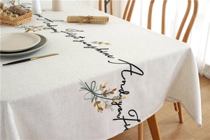 Close-up of linen tablecloth with floral embroidery and cursive letter patterns