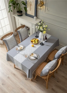 Close-up of geometric wave pattern and cream tassels on a gray rectangular tablecloth