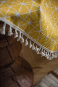 Close-up of yellow geometric print fabric with white tassels and cotton-polyester texture