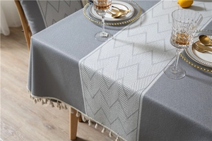 Detailed view of dark grey table runner with white geometric patterns and tassel trim