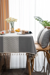 Close-up of gray jacquard table cloth featuring fringe edges and herringbone patterns