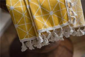 Detailed macro view of yellow geometric star pattern fabric with white fringe tassels