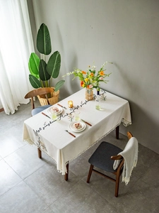 Detail of beige rectangular tablecloth with floral embroidery, fringe edges and cotton texture