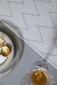 Macro shot of gray herringbone weave tablecloth with elegant tassel trim and gold cutlery