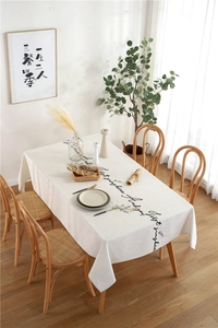Detail of cream linen tablecloth featuring floral letter embroidery and elegant draping