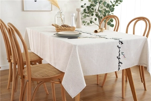 Detail of embroidered floral patterns and cursive text on linen-textured tablecloth