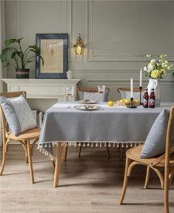 Close-up of light grey jacquard tablecloth with geometric patterns and white fringe edge