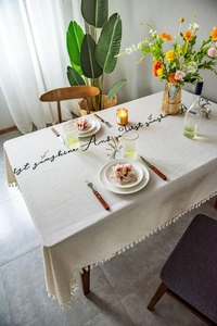 Detail of embroidered floral tablecloth with tassels and black script text decoration