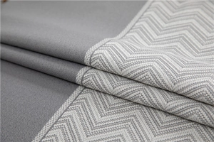 Detailed view of grey jacquard fabric featuring woven wave patterns and fringe textures