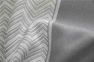 Macro detail of grey jacquard table cloth featuring wavy fringe and geometric weave texture