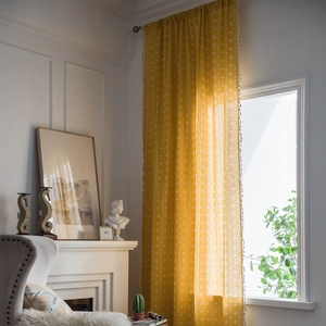 Yellow geometric hexagon curtains with pom-pom tassels in a sunlit modern interior