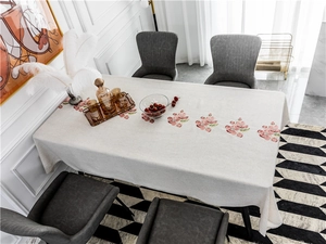 Detailed pink floral embroidery on linen-textured rectangular tablecloth with stitched edges