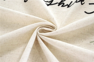 Close-up of beige linen tablecloth fabric showing natural fiber texture and black embroidery