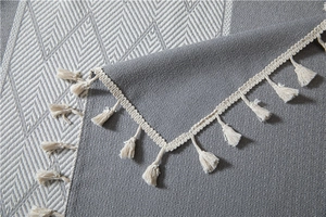 Macro shot of grey chevron jacquard tablecloth featuring handcrafted white fringe edges