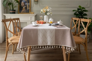 Macro detail of earthy pink jacquard tablecloth with geometric patterns and white tassels