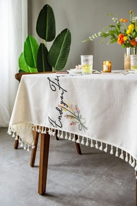 Detail of embroidered floral tablecloth with Enjoy your life text and tassel edges