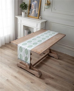 Detail of chenille table runner featuring leaf patterns and beaded tassel fringe on wood