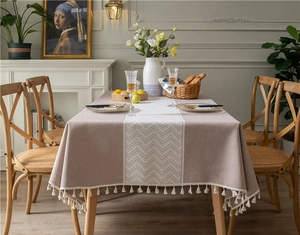 Detailed view of khaki jacquard tablecloth featuring white herringbone stripes and fringe