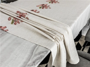 Detail of embroidered peach blossom pattern on off-white cotton linen tablecloth edge