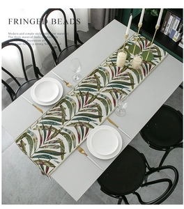 Close-up of Nordic table runner featuring tropical palm leaf patterns and fringe beads