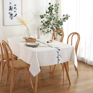 Linen rectangular tablecloth with floral embroidery and cursive lettering in a cozy dining room