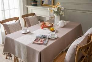 Detail of beige geometric jacquard tablecloth featuring elegant tassel edges and rich textures