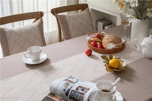 Detail of beige geometric jacquard tablecloth with textured tassels and ripple patterns