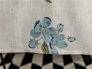 Close-up of blue floral embroidery and natural linen texture on a fresh table runner