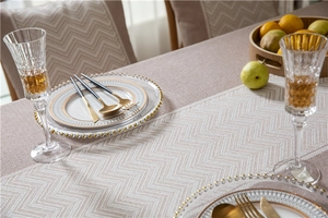 Macro detail of beige jacquard tablecloth featuring herringbone pattern and wavy fringe edges