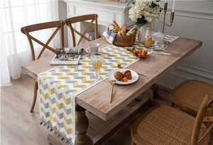 Detail of yellow and grey jacquard chenille table runner with fringe pompom edges