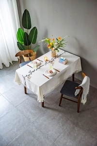 Close-up of embroidered flowers and cursive text on a linen tablecloth with tassels