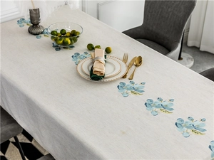 Detailed blue flower embroidery on rustic linen rectangular tablecloth in dining room