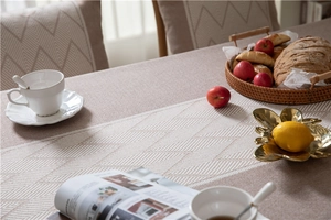 Detailed view of beige jacquard tablecloth with chevron pattern and hanging tassels