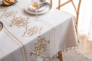 Detail of floral embroidery and tassel fringe on beige linen tablecloth for dining tables
