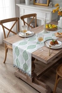Detail of chenille table runner featuring jacquard leaf patterns and blue bead tassels