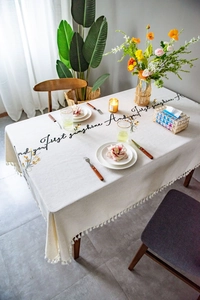 Detail of embroidered floral pattern and fringe edge on cream rectangle tablecloth