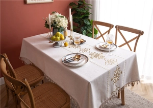 Close-up of golden vintage embroidery and decorative tassels on beige linen tablecloth
