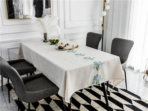 Detailed texture of beige linen tablecloth featuring elegant blue floral embroidery