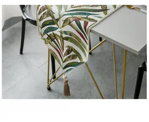 Close-up of chenille table runner with tropical leaf patterns and elegant tassel edge