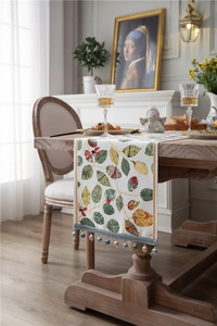 Detail of chenille table runner featuring realistic autumn leaves and beaded tassel fringe